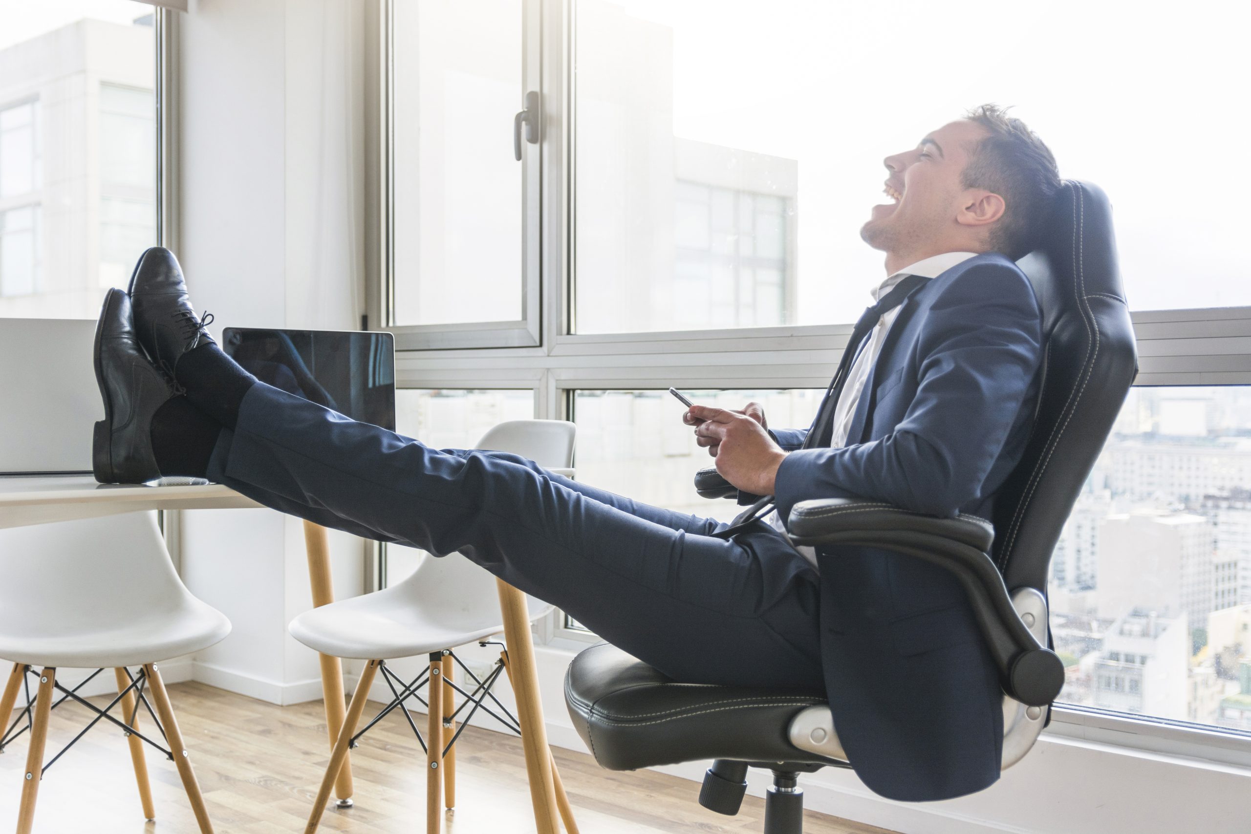 happy-businessman-sitting-chair-workplace-using-mobile